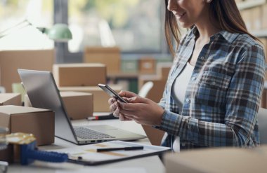 Gülümseyen bir e-ticaret uzmanı masada oturuyor ve akıllı telefon, teknoloji ve iletişim konsepti kullanıyor.