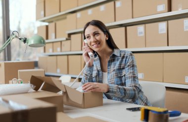 E-ticaret mağazası sahibi telefonla sipariş alıyor ve müşterilerle konuşuyor.
