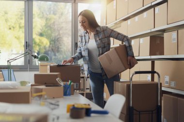 Bir depoda teslimat kutuları hazırlayan kadın: e-ticaret ve sevkiyat konsepti