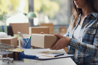 Depoda elinde küçük bir teslimat kutusu tutan kadın: e-ticaret ve sevkiyat konsepti