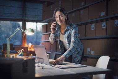 E-ticaret mağazası sahibi telefonla sipariş alıyor ve müşterilerle konuşuyor.