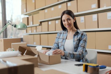 Mutlu kadın eşyaları bir teslimat kutusuna koyup bir sevkiyat, e-ticaret ve küçük işletme konsepti hazırlıyor.