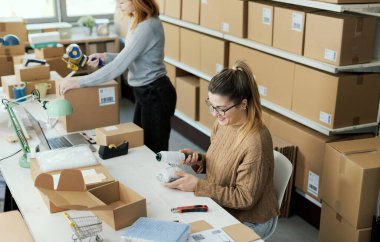 Depoda çalışan nakliye memuru, plastik ambalaj ve e-ticaret konseptiyle eşyaları paketliyor.