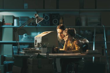 Baba ve oğul geceleri garajda eski bir bilgisayar kullanıyorlar ve birlikte oyun oynuyorlar.