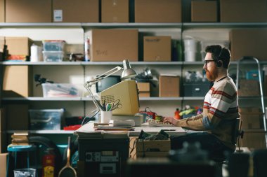 Eski tarz programcı masasında oturuyor ve evindeki bodrumunda eski bir bilgisayarla çalışıyor.