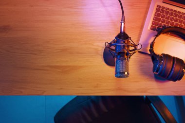 Professional audio equipment on the desk in the home studio: microphone, headphones and laptop, top view clipart