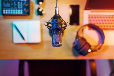 Profesyonel ses donanımı, not defteri, dizüstü bilgisayar ve akıllı telefon ev stüdyosundaki masada, mikrofon ön planda, üst görünümde: içerik oluşturma, canlı yayını ve eğlence konsepti