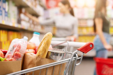 Markette tam alışveriş arabası ve arka planda müşteriler, market alışverişi ve ticaret konsepti