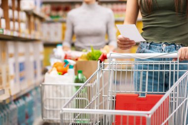 Alışverişçinin elinde bir market listesi var ve boş bir tramvay, market alışverişi konsepti, tanınmayan insanlar.