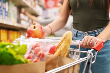 Marketten alışveriş yapan müşteri, alışveriş arabasına ürünler koyuyor, market alışverişi konsepti.