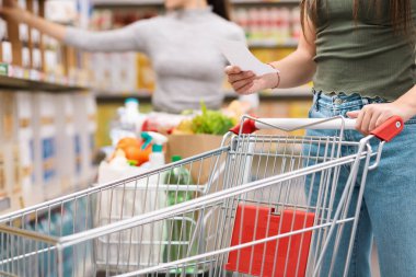 Alışverişçinin elinde bir market listesi var ve boş bir tramvay, market alışverişi konsepti, tanınmayan insanlar.
