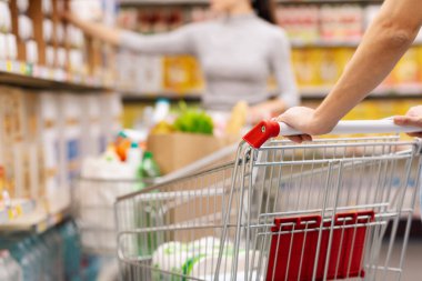 Bakkaldan alışveriş yapan ve süpermarkette alışveriş arabası satan bir kadın: market alışverişi, ticaret ve yaşam tarzı kavramı