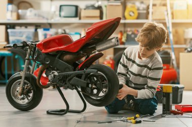 Garajda motosikletini tamir eden yakışıklı tamirci çocuk.