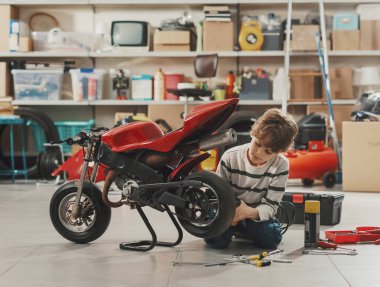 Garajda motosikletini tamir eden yakışıklı tamirci çocuk.