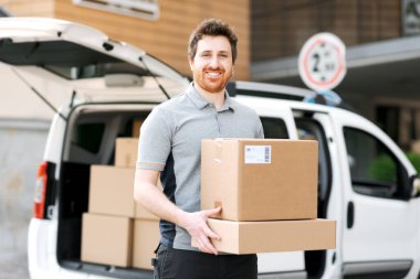 Paket taşıyan ve sokakta yürüyen gülümseyen bir teslimatçının portresi.