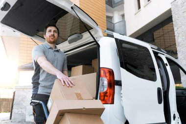 Eve paket getiren kurye: Şehir sokaklarında kutu taşıyan bir adam el arabası kullanıyor.