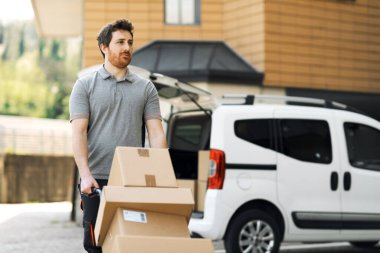 Eve paket getiren kurye: Şehir sokaklarında kutu taşıyan bir adam el arabası kullanıyor.