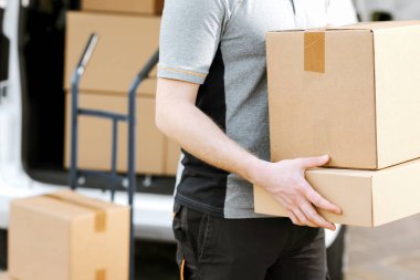 Express courier delivering packages at home, van and hand truck in the background, close up