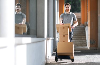 Profesyonel teslimatçı, şehirde el arabası kullanarak paket taşıyor.