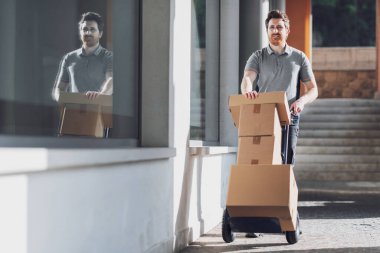 Profesyonel teslimatçı, şehirde el arabası kullanarak paket taşıyor.