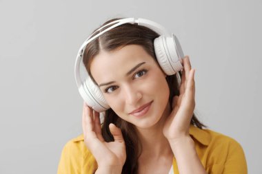 Güzel, gülümseyen, kablosuz kulaklık takan ve kamera, müzik ve eğlence konseptine bakan genç bir kadın.