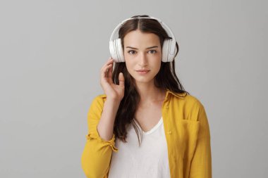 Güzel, gülümseyen, kablosuz kulaklık takan ve kamera, müzik ve eğlence konseptine bakan genç bir kadın.
