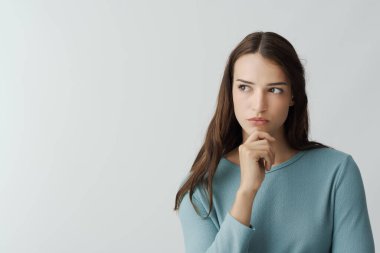 Güzel bir genç kadın, eli çenesinde, kararlar ve fırsatlar konseptiyle düşünür.