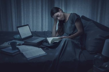 Young student pulling an all-nighter the night before the exam, she is reading her textbook and trying to focus clipart