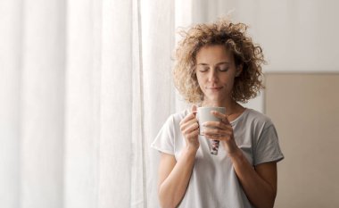 Mutlu, rahat bir kadın uyanıyor ve kahve içiyor. Sağlıklı yaşam tarzı kavramı.