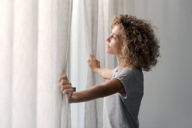 Serene genç kadın sabah uyanıyor ve pencereden dışarı bakıyor, sağlıklı yaşam tarzı konsepti