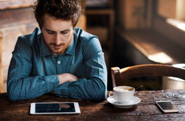 Hippi adam, dokunmatik ekran tabletini kırsal ahşap bir masada gevşetiyor.