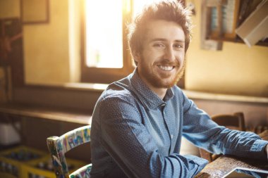 Neşeli hippi genç adam kameraya poz veriyor ve gülümsüyor.