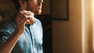 Aç genç hipster adam jambon, lezzetli bir sandviç yeme el kadar yakın