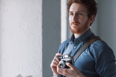 Hipster adam onun fotoğraf çekim ve vintage bir kamera tutmak için ilginç bir konu için arama