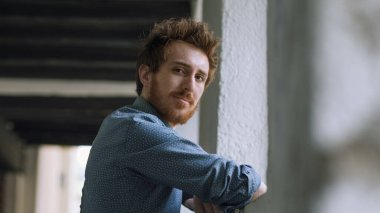 Genç kendine güvenen hippi kameraya bakıyor ve duvara yaslanıyor.