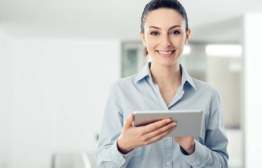 Genç gülümseyen bir dijital değmek perde tablet ve apps kullanarak iş kadın, o ofiste duruyor