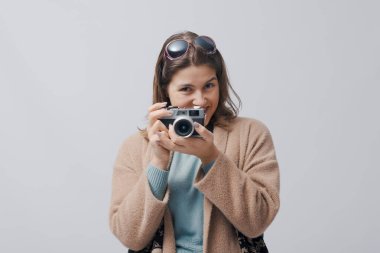 Beyaz arka planda izole edilmiş, klasik analog film kamerası kullanan mutlu bir kadın.