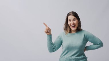 Neşeli kadın kameraya gülümsüyor ve parmağını boş fotokopi alanına doğrultuyor.