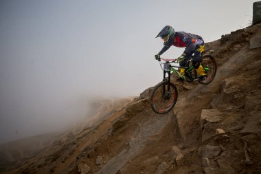 Yokuş aşağı bir MTB binicisi, arka planda Pasifik Okyanusu ve Lima şehrinin görkemli manzarasıyla El Morro Solar 'ın engebeli hatlarını oyuyor..