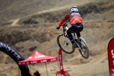 Yokuş aşağı bir MTB binicisi, arka planda Pasifik Okyanusu ve Lima şehrinin görkemli manzarasıyla El Morro Solar 'ın engebeli hatlarını oyuyor..