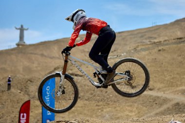 Yokuş aşağı bir MTB binicisi, arka planda Pasifik Okyanusu ve Lima şehrinin görkemli manzarasıyla El Morro Solar 'ın engebeli hatlarını oyuyor..