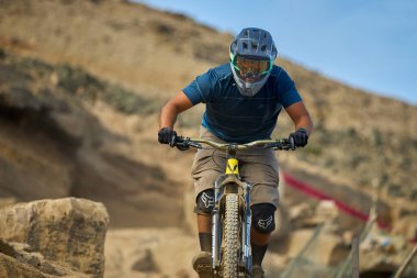 Yokuş aşağı bir MTB binicisi, arka planda Pasifik Okyanusu ve Lima şehrinin görkemli manzarasıyla El Morro Solar 'ın engebeli hatlarını oyuyor..