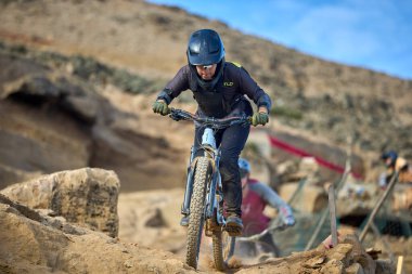 Yokuş aşağı bir MTB binicisi, arka planda Pasifik Okyanusu ve Lima şehrinin görkemli manzarasıyla El Morro Solar 'ın engebeli hatlarını oyuyor..