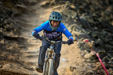 Yokuş aşağı bir MTB binicisi, arka planda Pasifik Okyanusu ve Lima şehrinin görkemli manzarasıyla El Morro Solar 'ın engebeli hatlarını oyuyor..