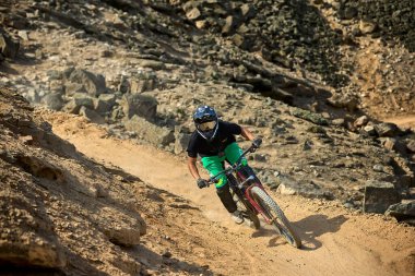 Yokuş aşağı bir MTB binicisi, arka planda Pasifik Okyanusu ve Lima şehrinin görkemli manzarasıyla El Morro Solar 'ın engebeli hatlarını oyuyor..