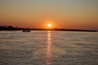 A sunset over the Zambezi River is a breathtaking sight. Imagine the sky painted in shades of orange, pink, and purple, reflecting off the smooth waters of the river. The sun hovers just above the horizon,  golden rays across the landscape