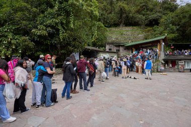 İstekli gezginlerden oluşan uzun bir kuyruk Machu Picchu 'nun girişine doğru ilerliyor. Her adım onları dünyanın en büyük harikalarından birine yaklaştırıyor. Beklemek, ötesinde bekleyen sihir için küçük bir bedel..