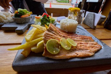 Bu gevrek trucha frita, Cusco usulü, yumuşak pirinç ve taze salatanın yanında altın ve aromalı servis edilir. Gelenek ve lezzetin mükemmel bir karışımı, dağlık sulardan tabağınıza kadar geliyor.