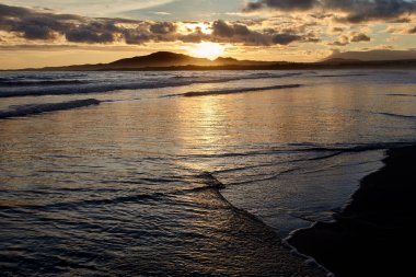 Galapagos Adaları üzerinde gün batımı nefes kesici bir doğa manzarasıdır. Güneş ufka doğru batarken, gökyüzü parlak renkli portakallar, koyu mor renkler ve pürüzsüz harmanlanmış yumuşak pembelerden oluşan bir tuvale dönüşür.. 