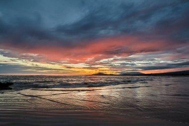 Galapagos Adaları üzerinde gün batımı nefes kesici bir doğa manzarasıdır. Güneş ufka doğru batarken, gökyüzü parlak renkli portakallar, koyu mor renkler ve pürüzsüz harmanlanmış yumuşak pembelerden oluşan bir tuvale dönüşür.. 